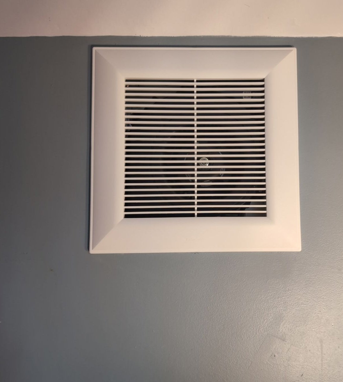 Bathroom exhaust fan grille finished flush in a completed bathroom